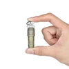 Hand holding a compact olive green Olight EDC keychain flashlight.