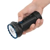 Hand holding a black and blue Olight Arkflex flashlight, showing its textured grip and control knob.