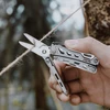 Hand using Nextool multitool scissors to cut jute twine outdoors
