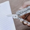 Hand using Nextool multi-tool scissors to cut notebook paper