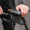 Man putting a wrench into an open grey bicycle saddle bag attached under a black bike seat