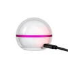 Spherical white LED night light with pink band charging via black USB cable on white background