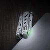 NexTool compact multi-tool with glowing green light on dark textured background