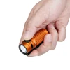 Olight Orange Baton 4 Premium Edition flashlight held in hand with pocket clip, for daily carrying and outdoor lighting.