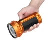 Hand holding Olight Marauder Mini orange high lumen flashlight with black rubber grip against white background
