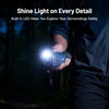 Hand holding a blue Topdon monocular with a bright LED light illuminating dark surroundings, showing outdoor exploration.