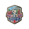 Olight UK 8th anniversary commemorative badge featuring Union Jack flag, double-decker bus, and Stonehenge scenery