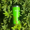 Green Olight insulated travel tumbler with red splatter pattern nestled in lush green leafy bushes in sunlight